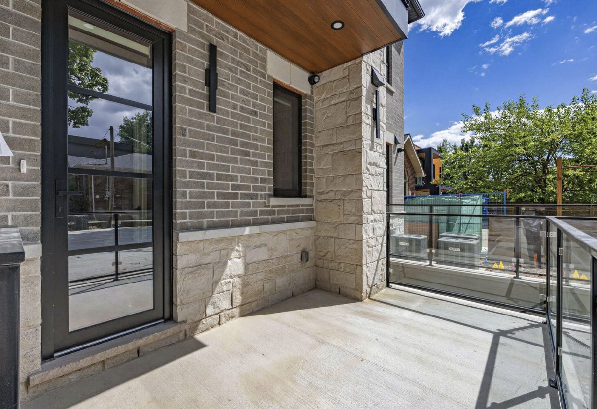 Balcony with brick, stone, wood soffit and glass railing