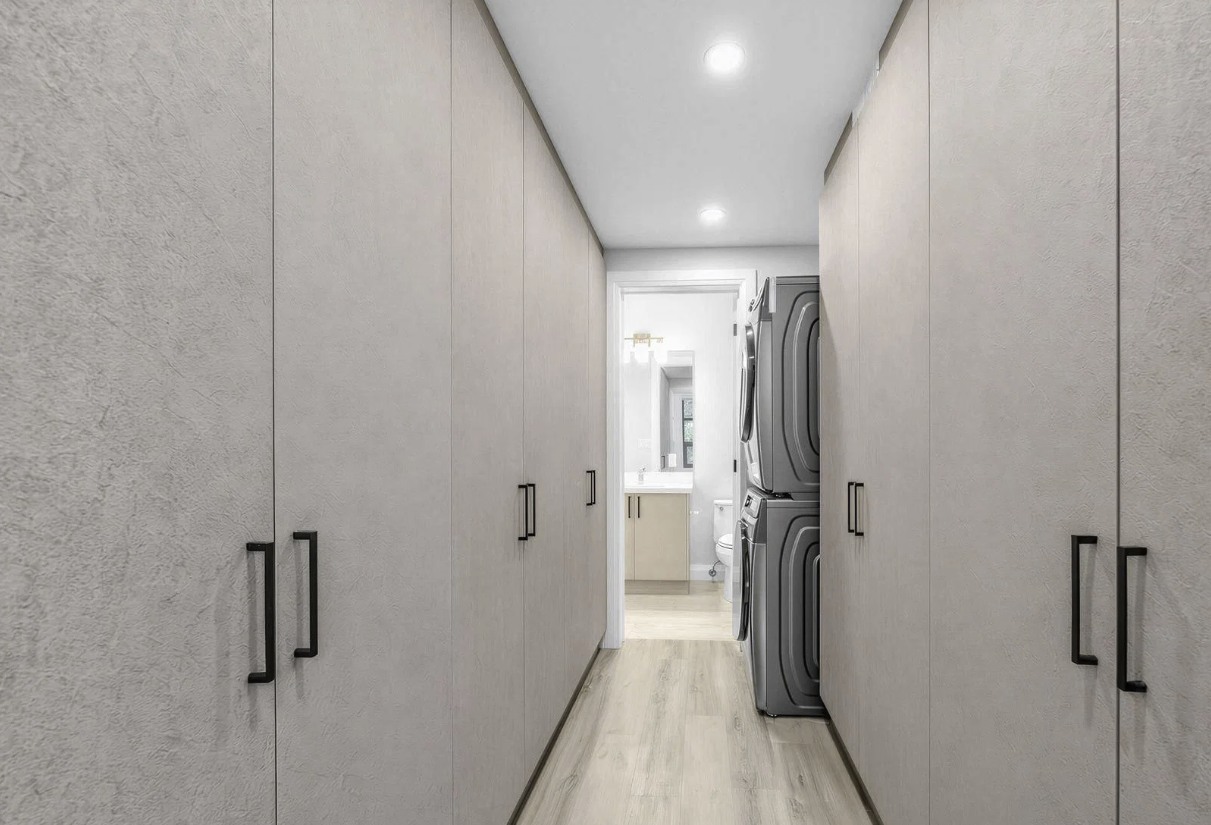 Hallway with floor-to-ceiling closets and laundry peek